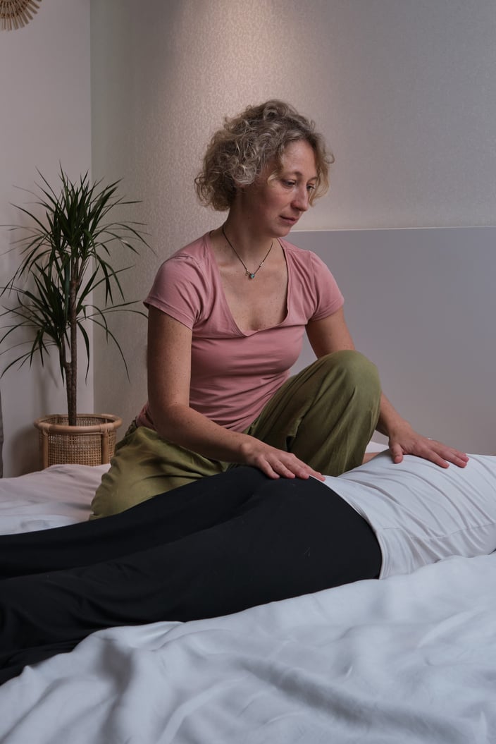 Two women perform somatic practices on a bed in a home bedroom